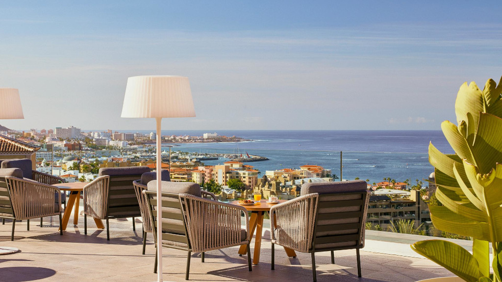 Rooftop terrace view over Costa Adeje, Tenerife with ocean and city skyline.