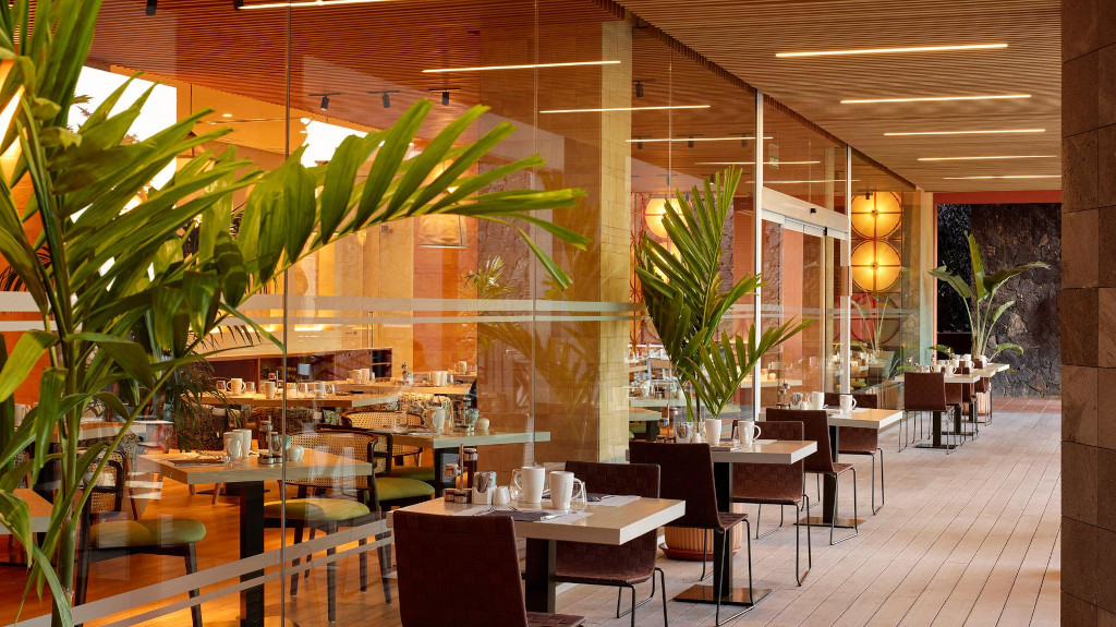 Outdoor dining area with tables and chairs set for breakfast in a Tenerife restaurant.