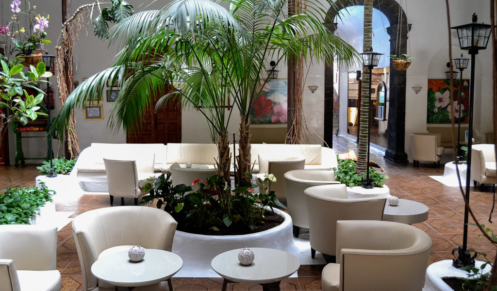 Indoor garden lounge with white seating, plants, and wall art in a Tenerife location.
