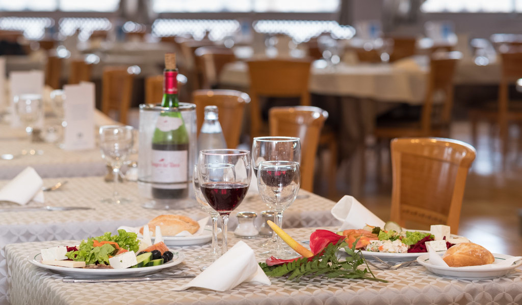 Table in restaurant in Tenerife with salads, red wine, and bread rolls.