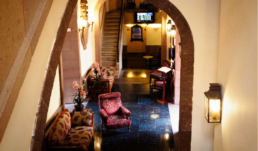 Lobby with chairs, tables, and plants under an archway in a hotel in Tenerife.