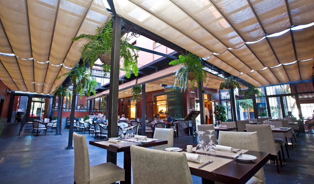 Outdoor dining area with tables and hanging plants in Tenerife restaurant.