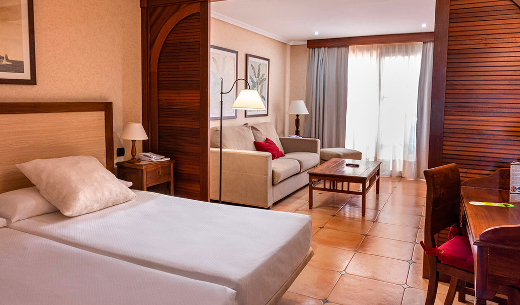 Hotel room with twin beds, couch, table, and window in Tenerife.