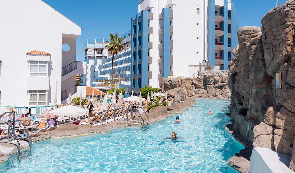 Outdoor pool with lounge chairs and people swimming at a Tenerife hotel.