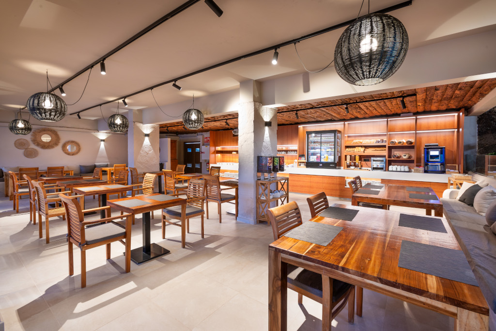 Dining area with wooden tables and chairs, warm lighting and island decor in Tenerife restaurant.
