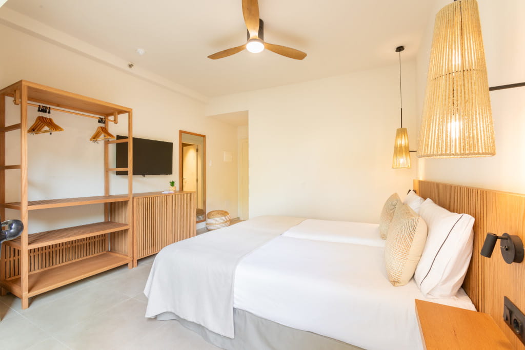 Hotel room with double bed, wicker lamps, open wardrobe, and TV in Tenerife.