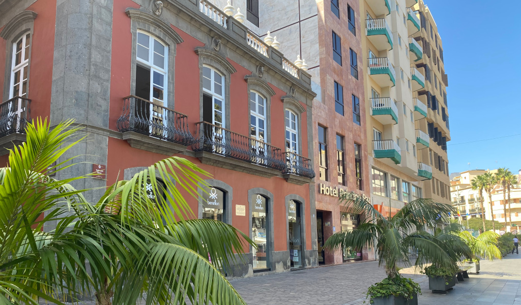 Facade of Hotel Marte in Tenerife with palm trees and adjoining historical building.
