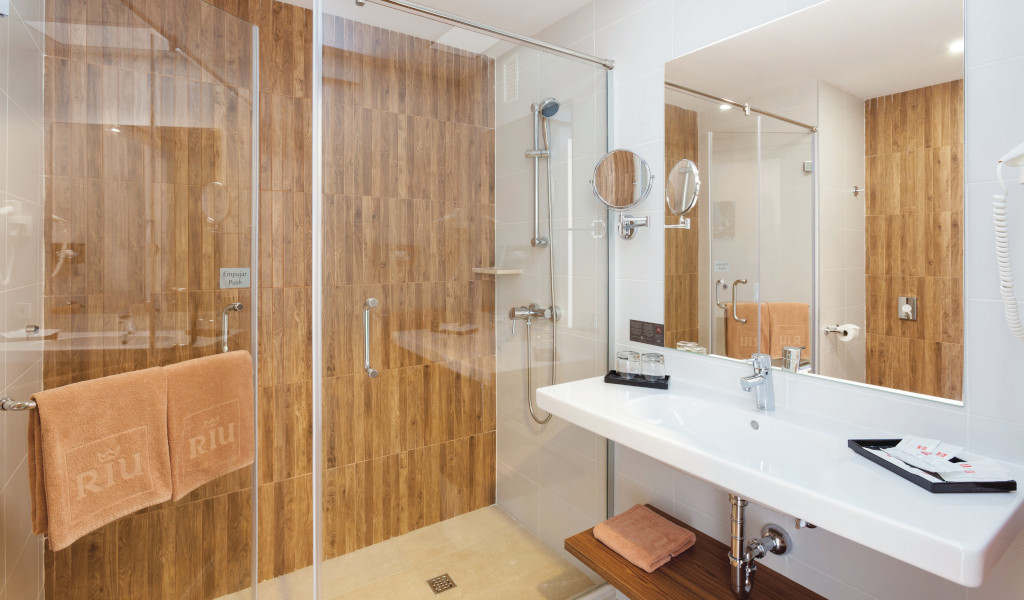 Hotel bathroom in Tenerife with shower and sink. Towels hanging, Riu brand.