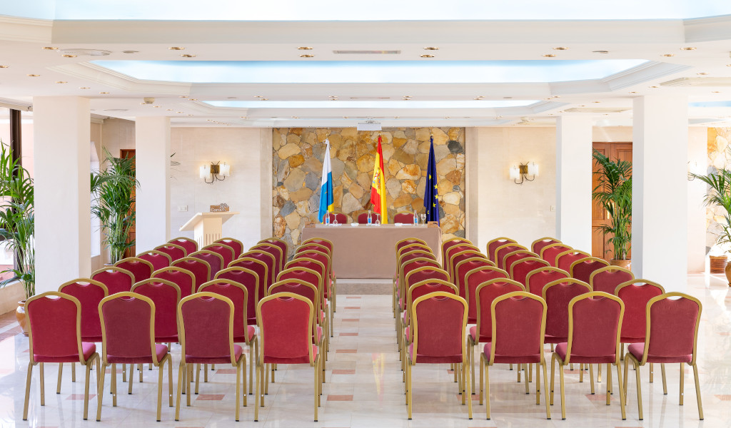 Conference room with rows of red chairs and flags in Puerto de la Cruz.