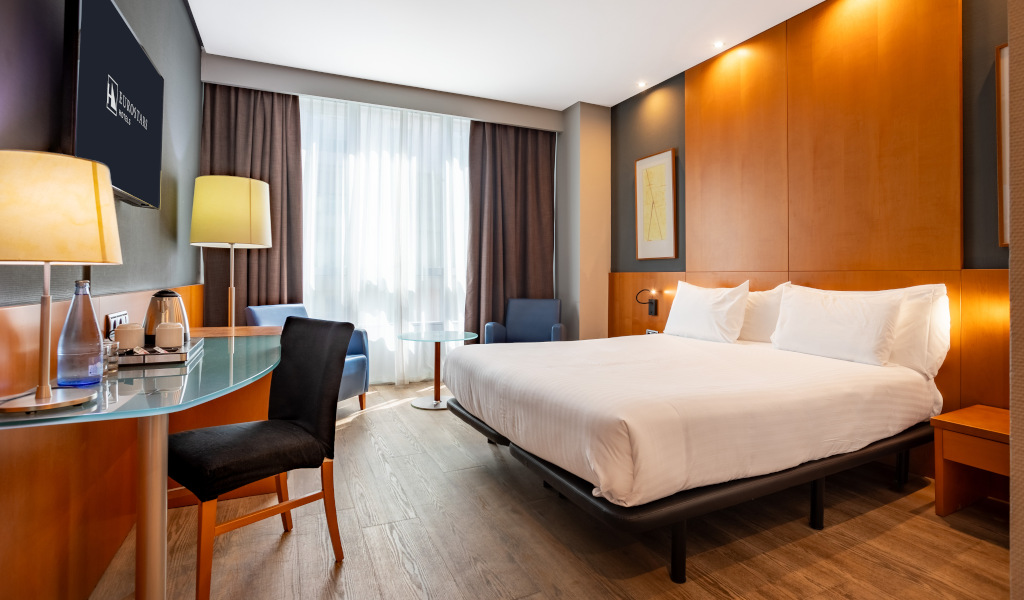 Hotel room with double bed, desk, lamps, chairs, and window at Auditorio Hotel in Tenerife.