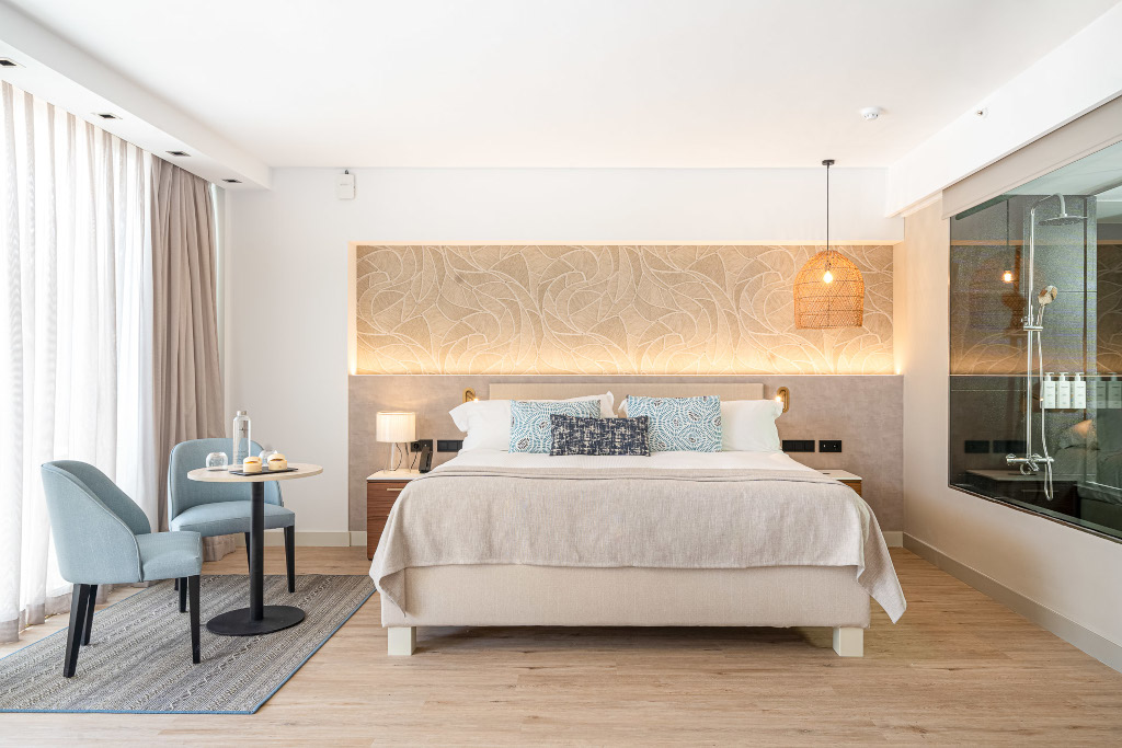 Hotel room in Tenerife with double bed, seating area, and glass-enclosed shower.