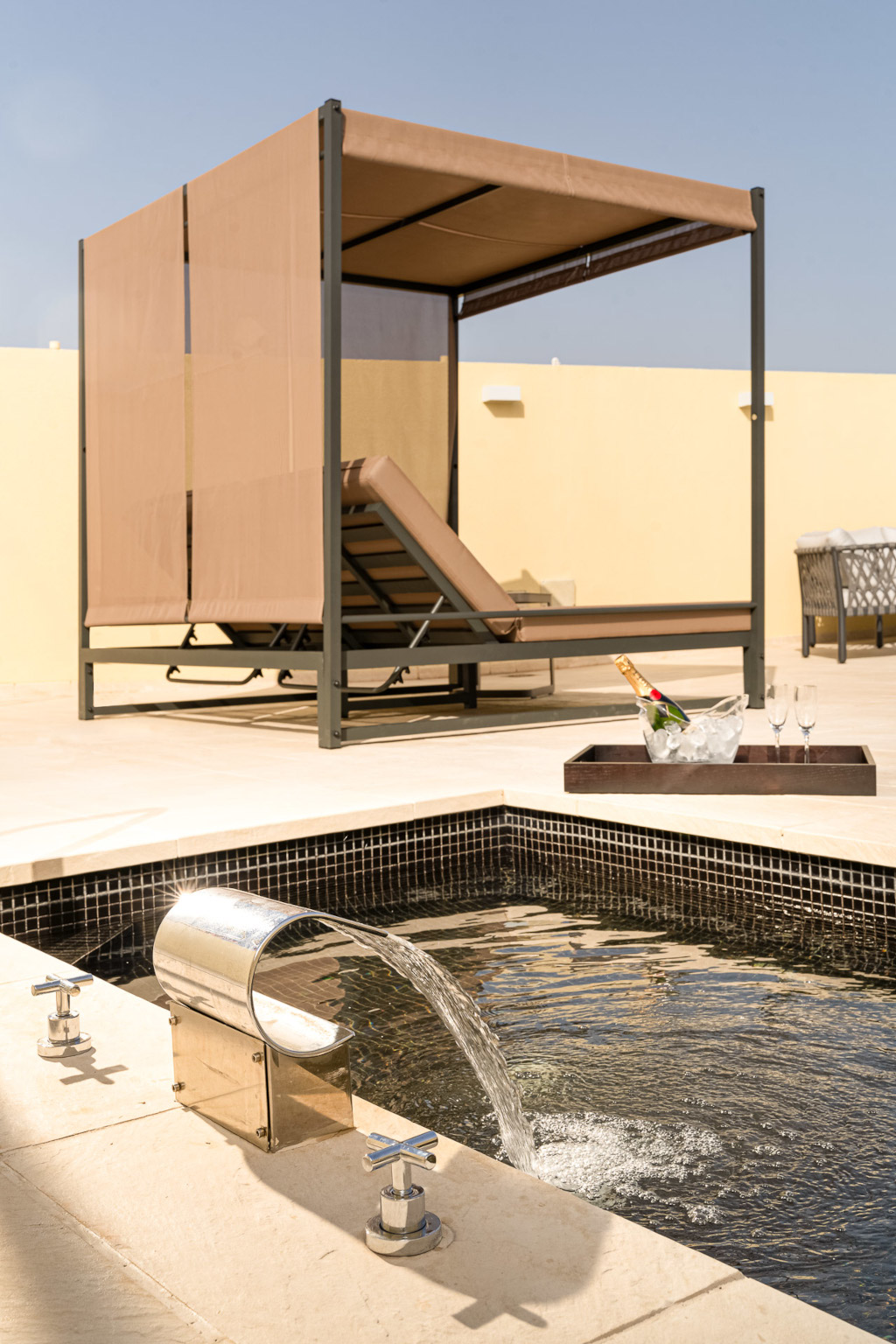 Poolside cabana with lounge chair, fountain, and champagne at a Tenerife resort.