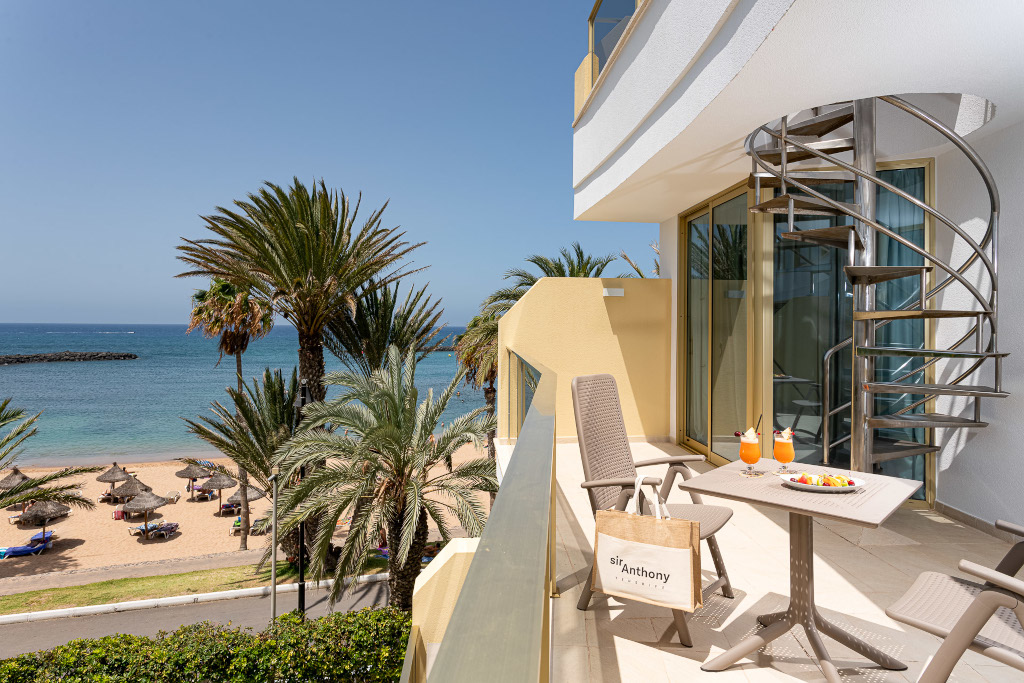 Balcony view of palm trees, sandy beach, and ocean in Sir Anthony, Tenerife.