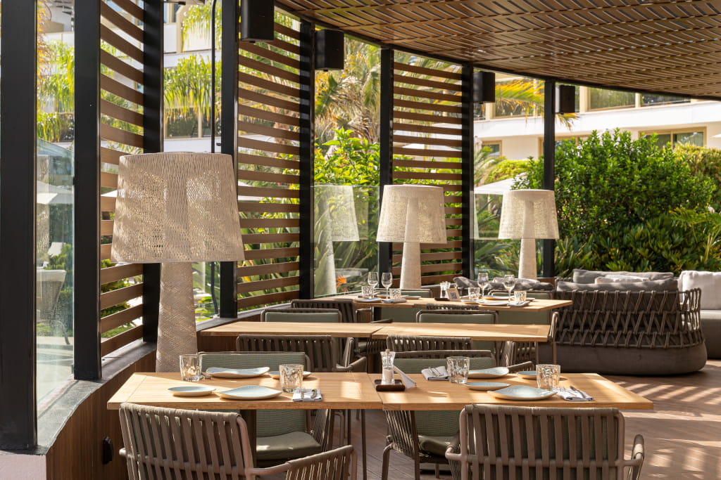 Outdoor dining area with wooden tables and elegant lamps in a Tenerife restaurant.