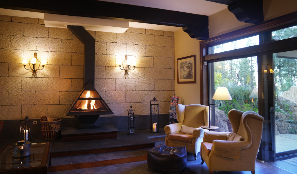 Cozy living room with fireplace, armchairs, and view of a garden in Tenerife.