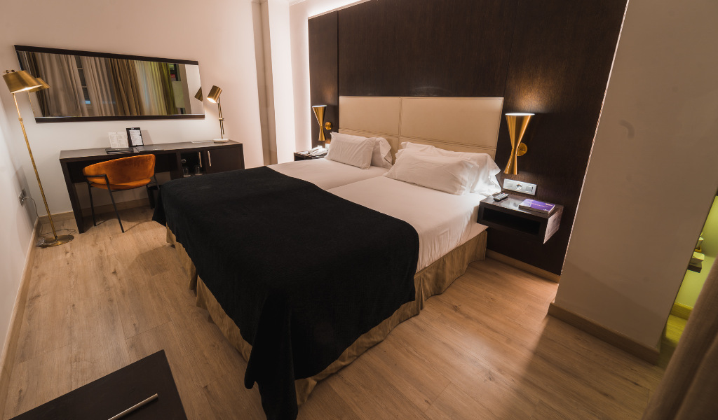 Two twin beds in a hotel room with a desk and mirror in Tenerife.