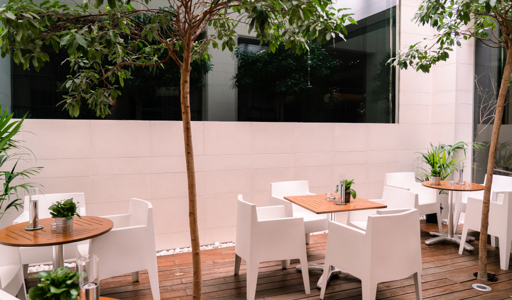 Outdoor café seating with white chairs and wooden tables in Tenerife patio.