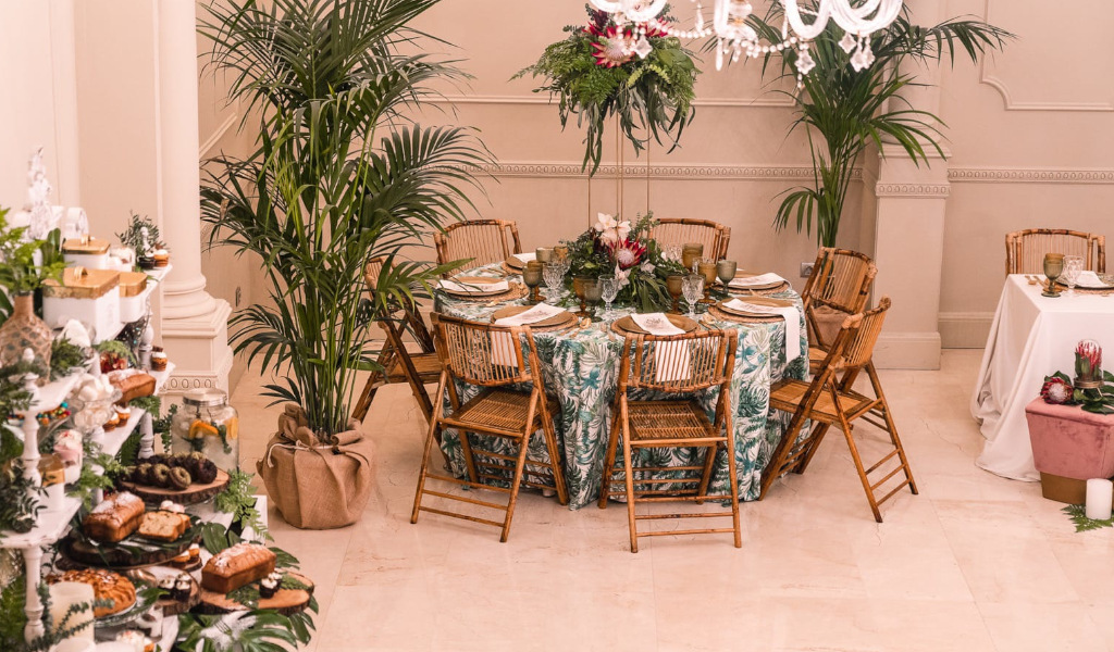 Table set for event with floral centerpiece and chairs, surrounded by plants in Tenerife.
