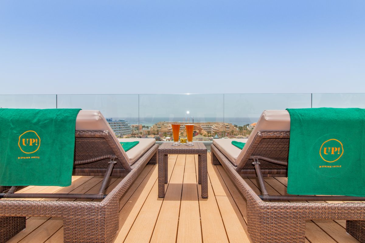 Two lounge chairs with green towels, drinks on table, overlooking Tenerife coast.