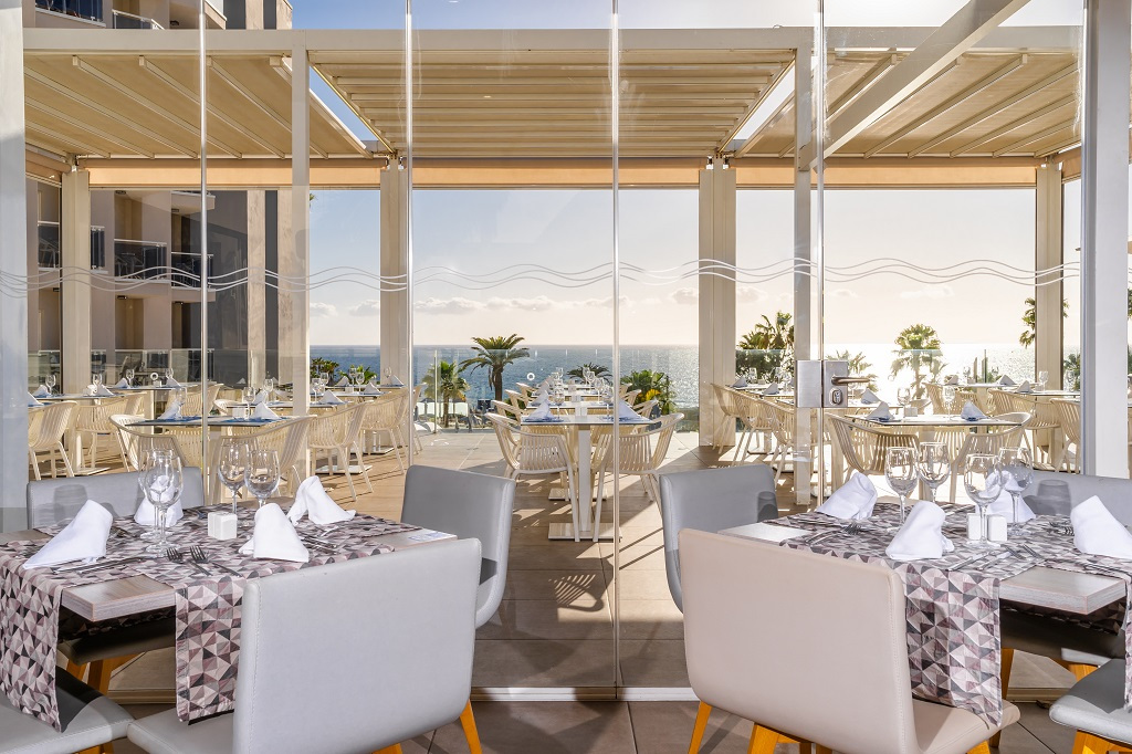Outdoor dining area with ocean view in Tenerife, set tables and chairs under a pergola.