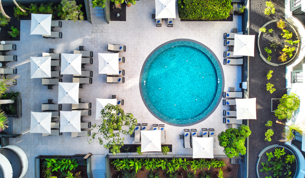 Outdoor pool and sun loungers with umbrellas surrounded by greenery in Tenerife.