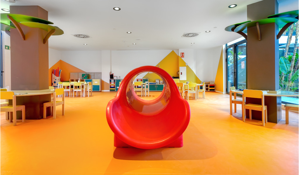 Children's playroom with orange floor, red slide, tables, and chairs in Tenerife.