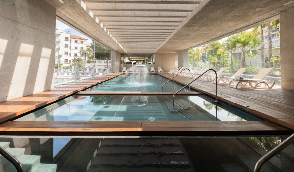 Indoor pool with sun loungers in Tenerife hotel, natural light filtering through the windows.