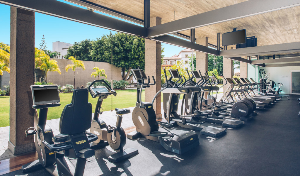 Row of exercise machines facing a garden view at a Tenerife gym.