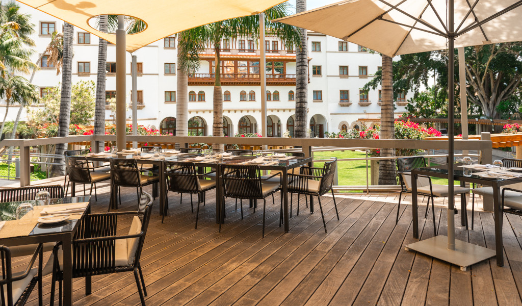 Outdoor restaurant terrace with tables and chairs overlooking tropical garden in Tenerife.