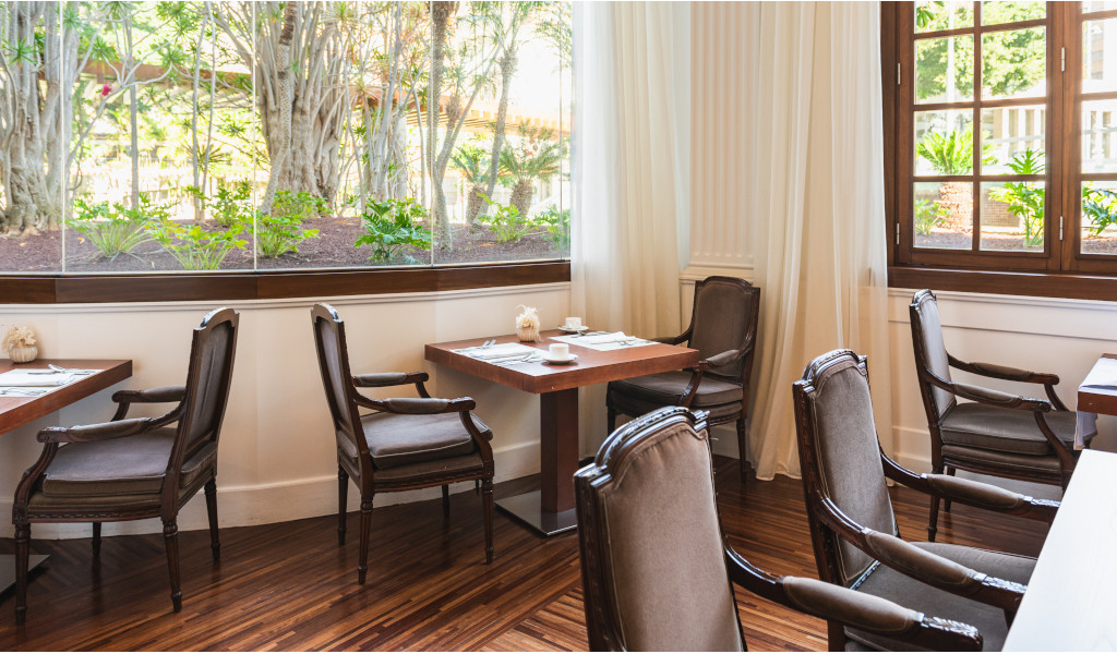 Dining area with tables and chairs near large windows in Tenerife restaurant.