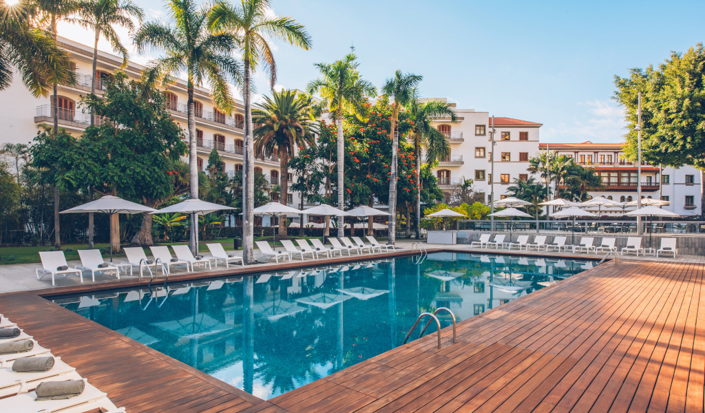 Outdoor pool with lounge chairs and umbrellas at a hotel in Tenerife.