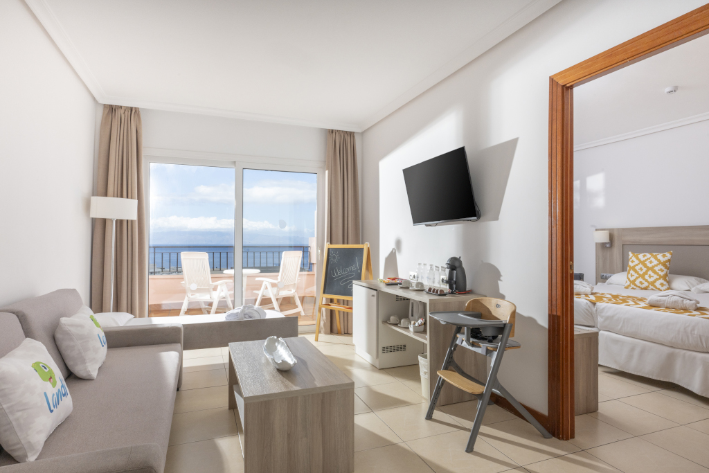 Living room and bedroom with ocean view, coffee station, and Welcome chalkboard in Tenerife.