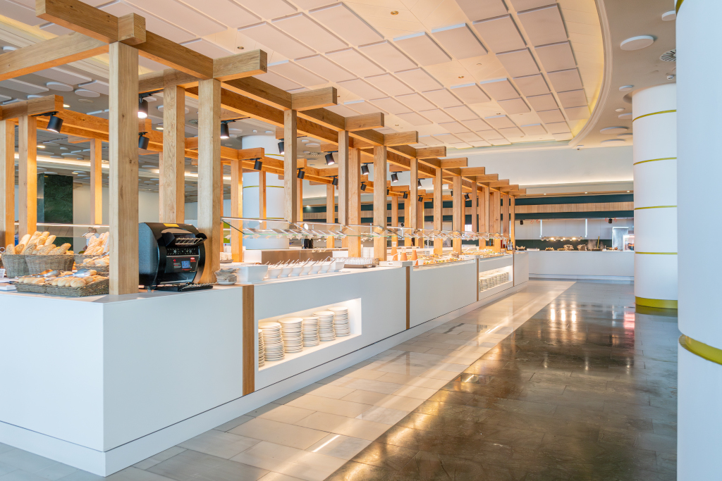 Buffet area with wooden beams, plates, bread baskets, and food station in Tenerife.