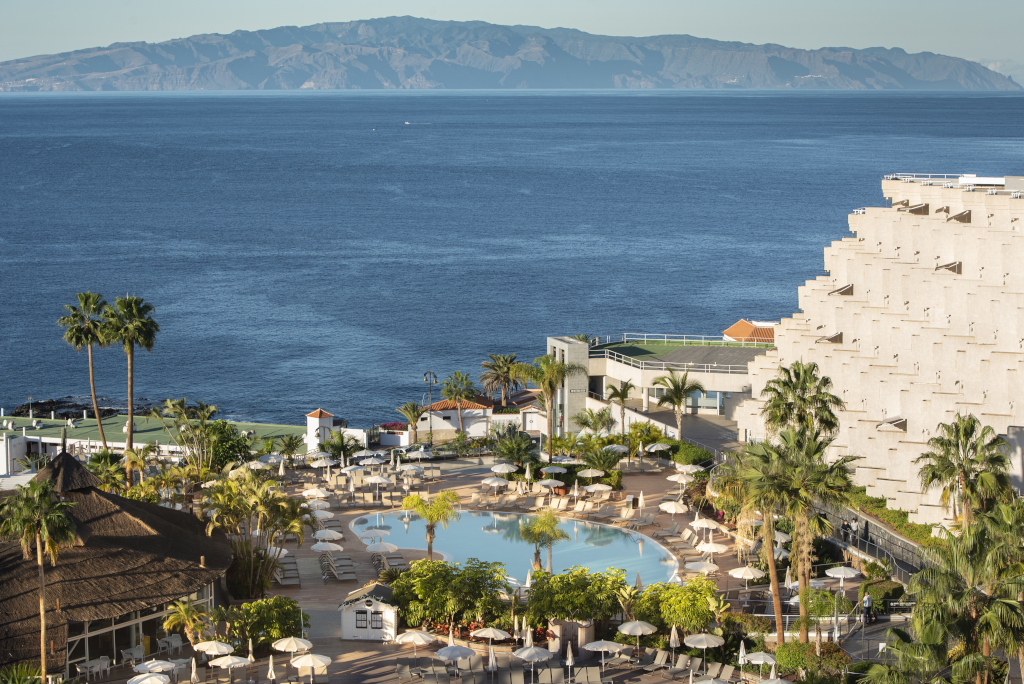 Rooftop pool view in Tenerife with ocean and distant island in background.