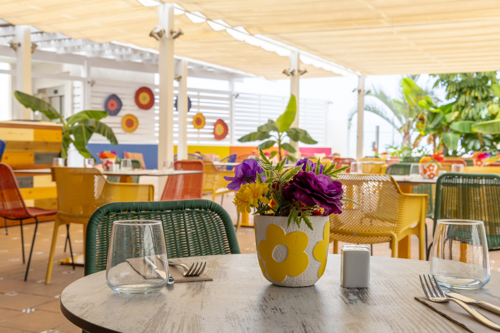 Outdoor restaurant seating in Tenerife with colorful chairs and flower centerpiece.
