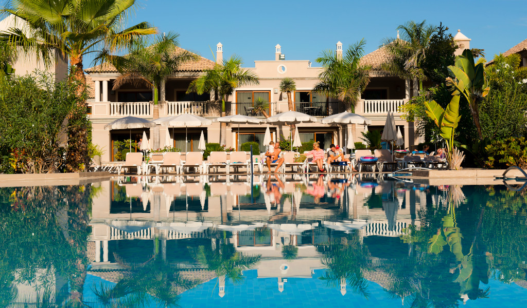 Luxury resort with swimming pool, sunbeds, and palm trees in Tenerife.
