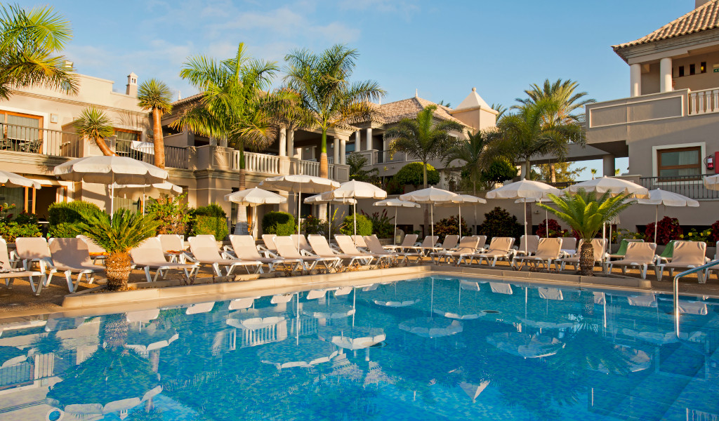 Outdoor pool area with sun loungers and umbrellas at a Tenerife resort.