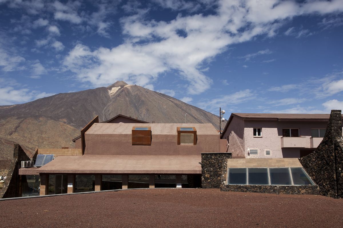 Building with Mount Teide in background, Tenerife, under a blue sky.