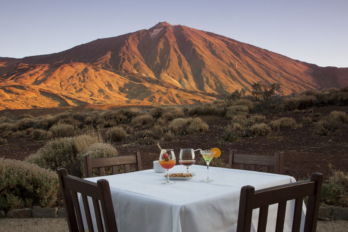 Table with drinks and chairs facing Mount Teide at sunset in Tenerife.