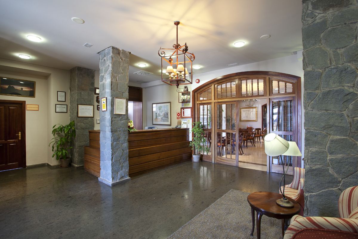 Hotel lobby in Tenerife with wooden reception desk and stone pillars.