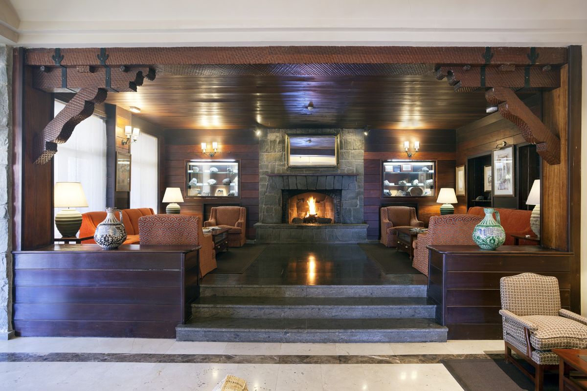Cozy hotel lounge in Tenerife with fireplace, armchairs, and decorative vases.