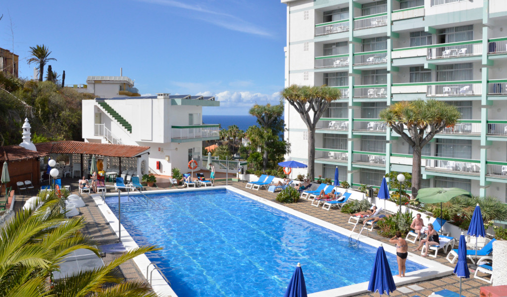 Outdoor pool and sunbathing area at a hotel in Tenerife with sea view.