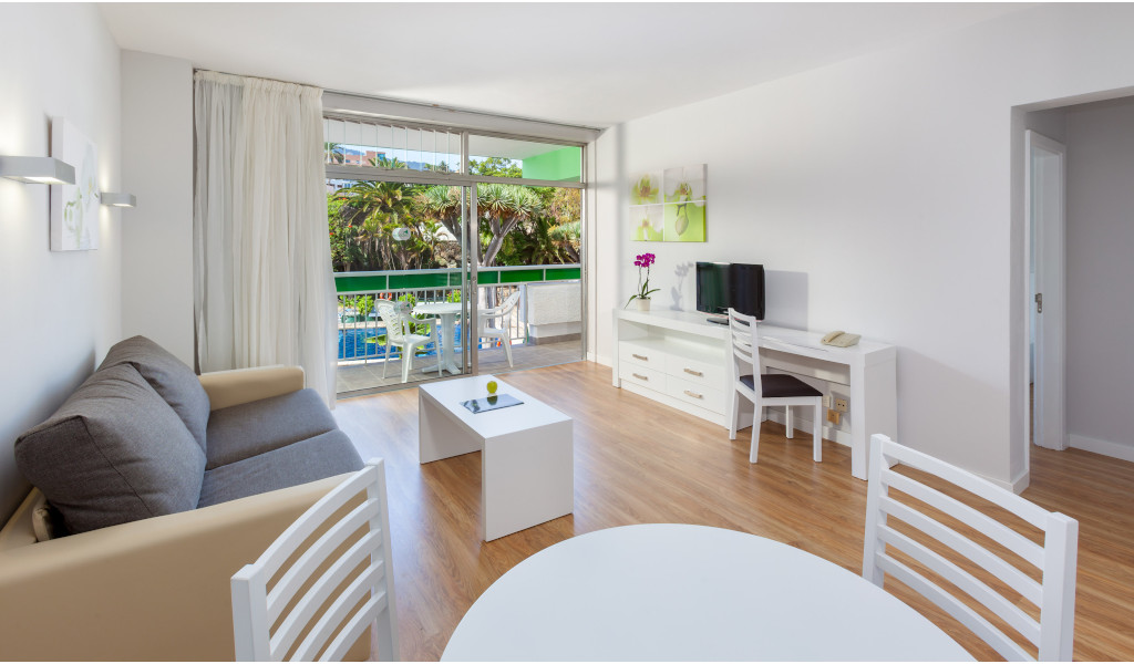 Living room with a sofa, table, TV, and balcony view in Tenerife.