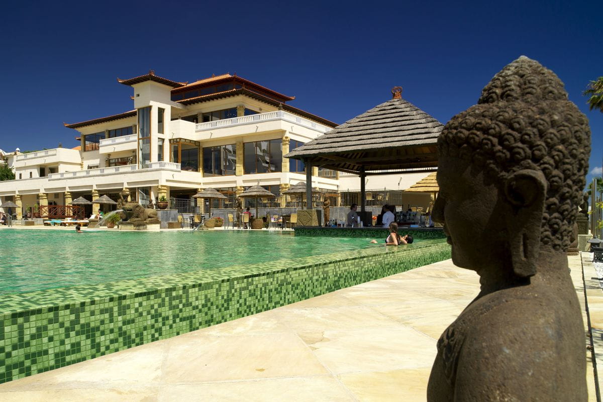 Statue near a pool and resort building in Tenerife.