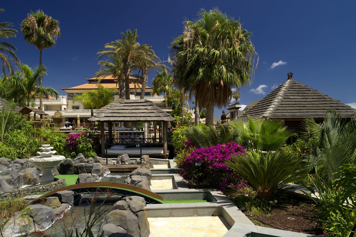 Tropical garden with thatched huts and palm trees in Tenerife.