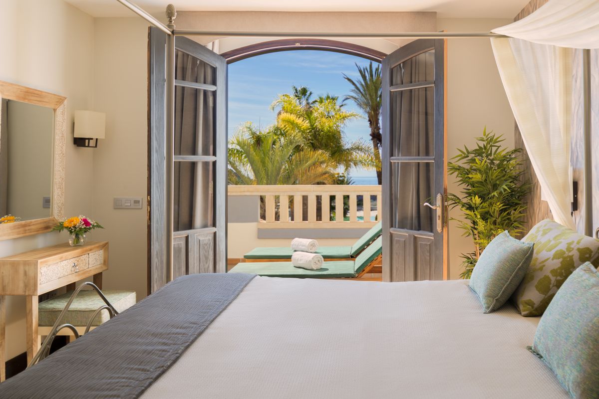 Bedroom view with open doors to balcony with palm trees in Tenerife.