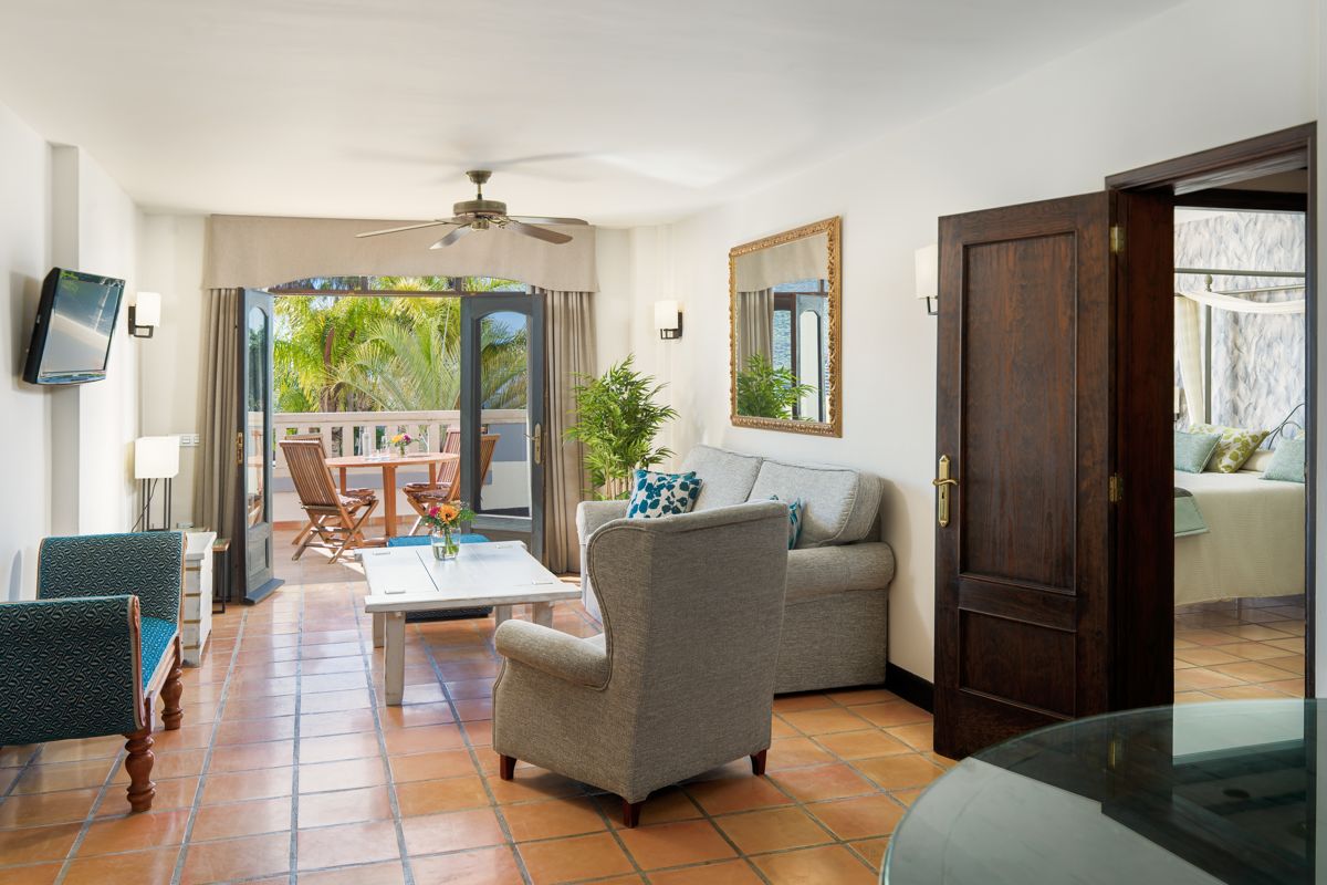 Living room with sofa, armchair, and balcony with table and chairs in Tenerife.