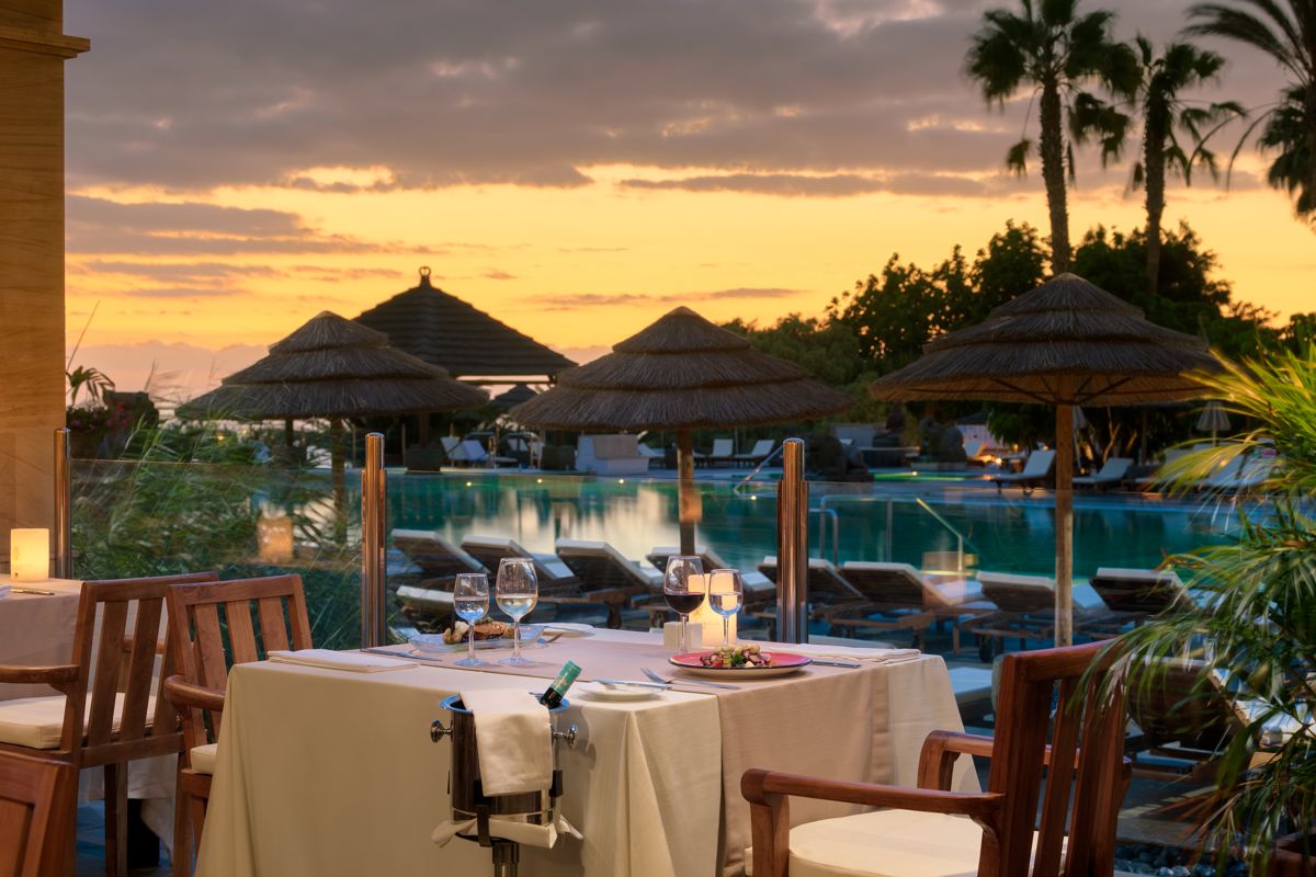 Outdoor dining setup by the pool at sunset in Tenerife.