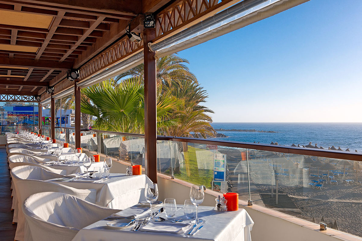 Outdoor dining area with ocean view in Tenerife, tables set for guests.