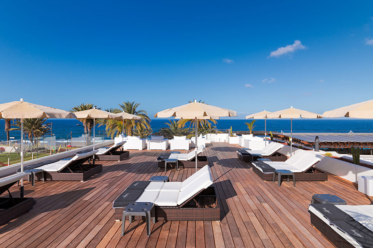 Rooftop terrace with sun loungers and umbrellas overlooking the ocean in Tenerife.